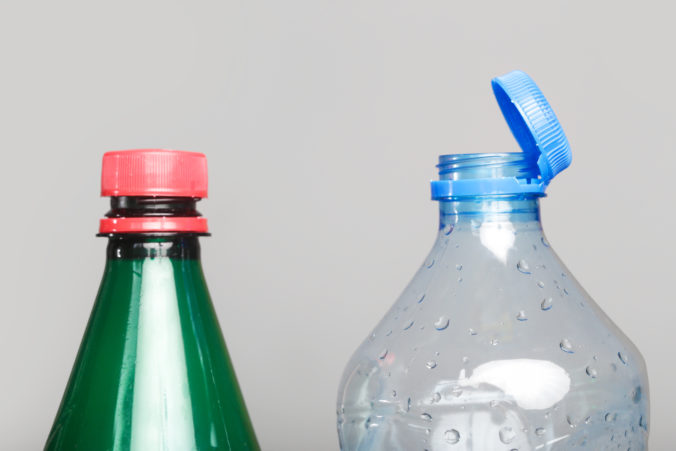 Example of older model and new cap attached to plastic bottle, connected to the neck of the bottle by solid tab attached to safety ring.