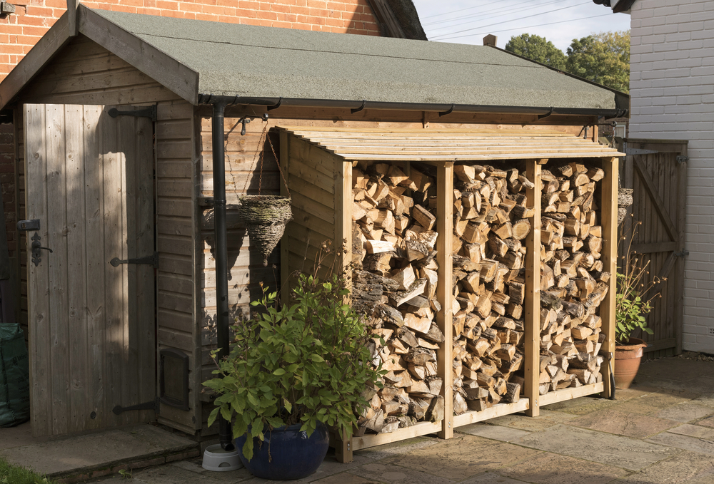 Log,Store,Standing,Against,A,Garden,Shed.,Logs,Stacked,In