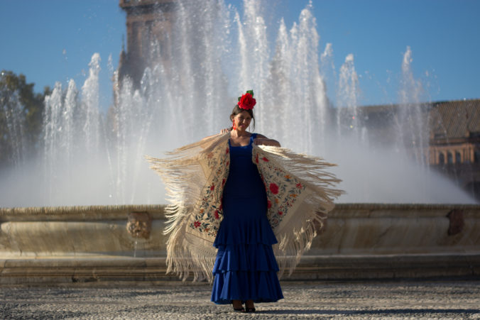 The girl dances flamenco with a shawl near the fountain