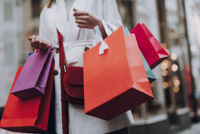 Elegant young woman with shopping bags standing on the street