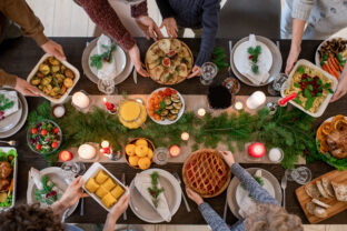 Top view of hands of family members holding plates with homemade food