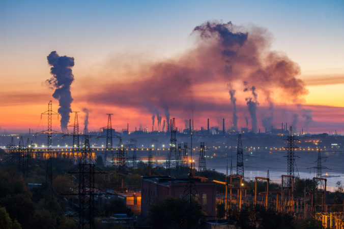 Industrial landscape of plant pipes producing toxic smoke with air pollution in the sky on sunset, hydroelectric dam and high voltage towers, Zaporizhzhia, Ukraine