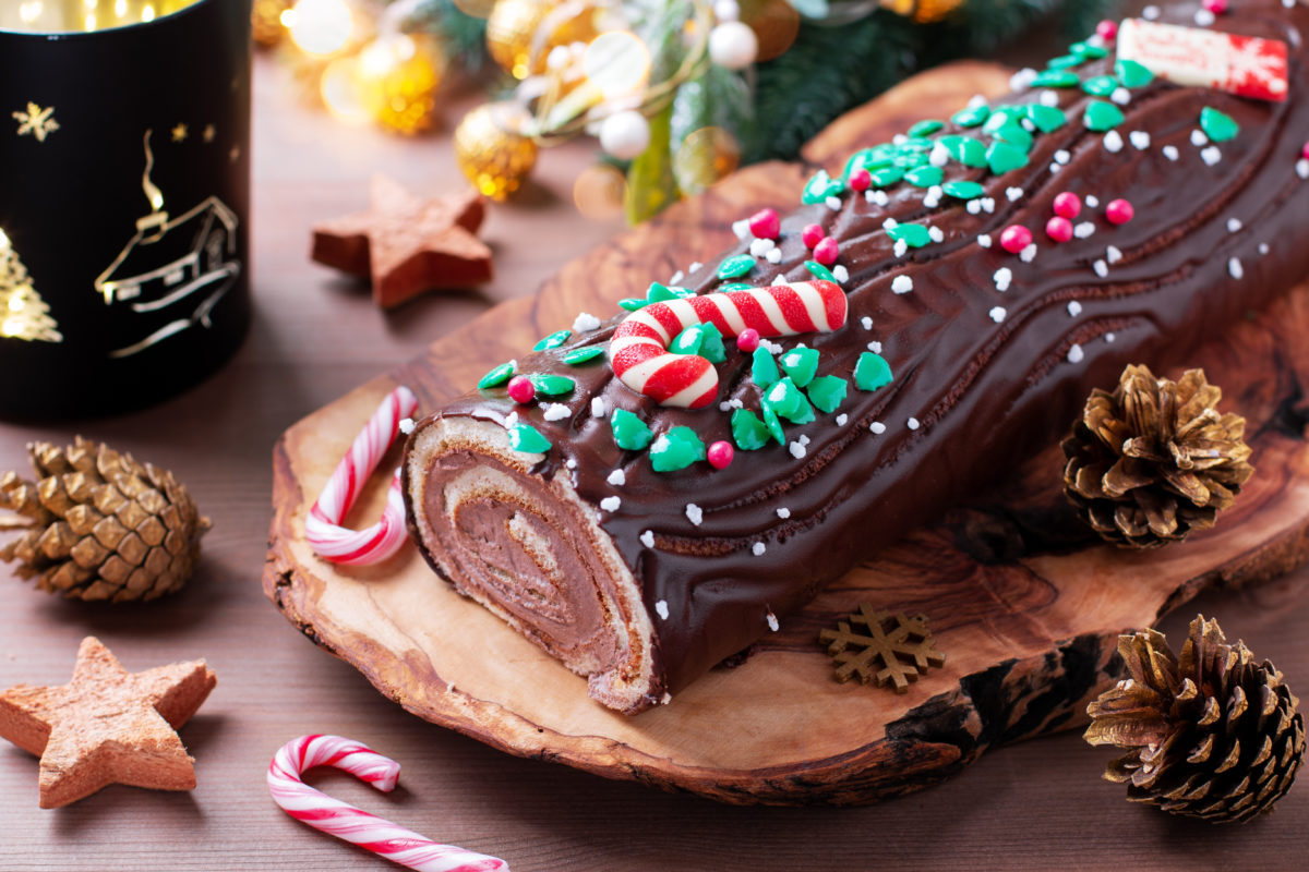 Traditional chocolate trunk cake or log cake on table with Christmas decorations