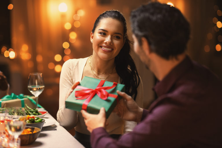 Happy friends giving christmas presents at home