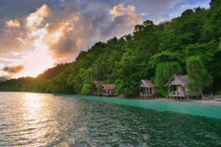 Beautiful sunset above typical wooden bungalows on the beach - Kri Island, Raja Ampat, West Papua, Indonesia