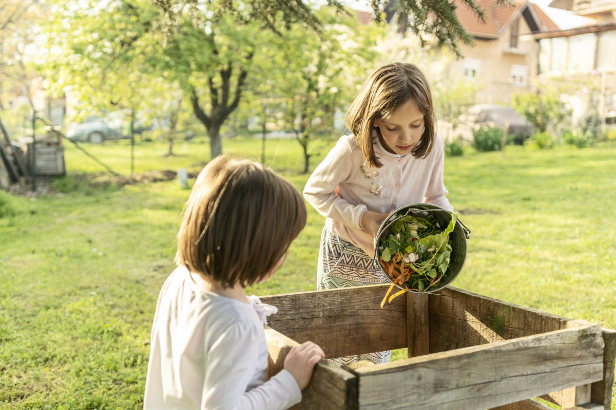 Children emptying kitchen waste in to a compost bin