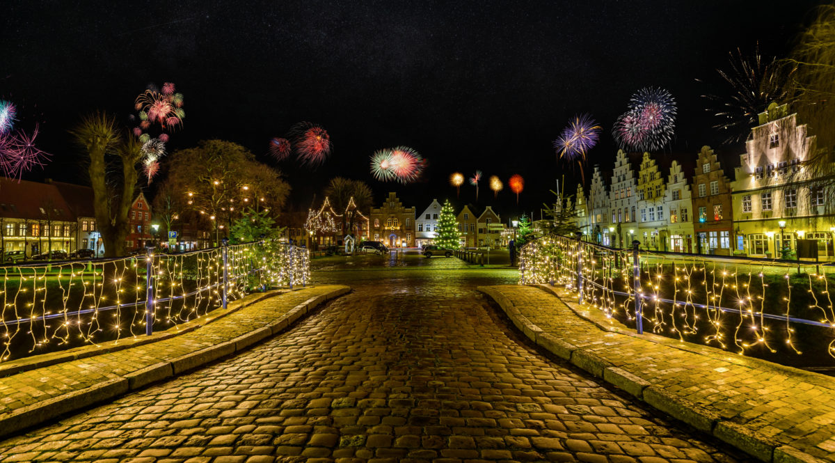 Charming town bathed in festive lighting and fireworks, creating a romantic atmosphere for New Year's Eve with the spectacular display of colors and lights. Friedrichstadt at night during the New Year