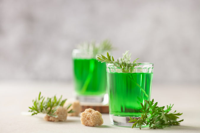 Absinthe drink in glass on light background with the absinthe plant and sugar
