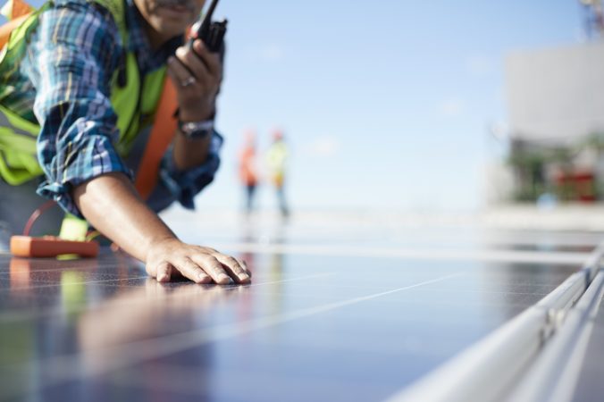 Engineer with walkie talkie inspecting solar panels at power plant