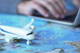 Airplane model closeup, defocused person booking flight tickets online on laptop
