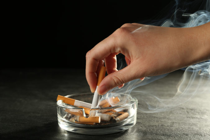 Woman extinguishing cigarette in glass ashtray