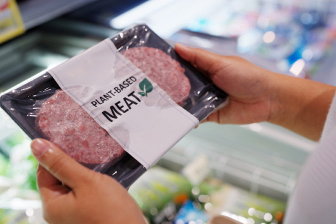 Close up hand carry choose zero pork soy bean faux peas cutlet gluten free read beyond non meat lab label. Buy raw fake beef tray in asia store veggie burger patty for health care eat diet meal cook.
