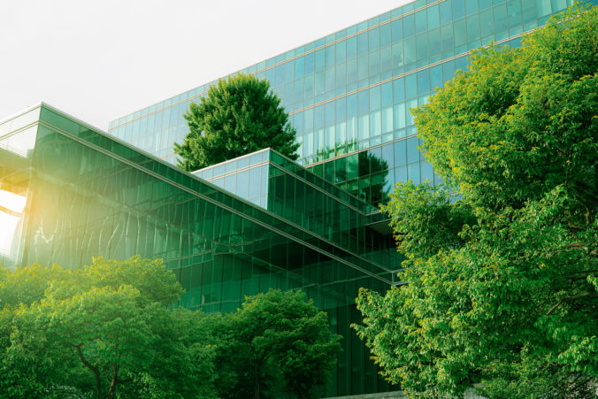 Sustainble green building. Eco friendly building. Sustainable glass office building with tree for reducing carbon dioxide. Office with green environment. Corporate building reduce CO2. Safety glass.