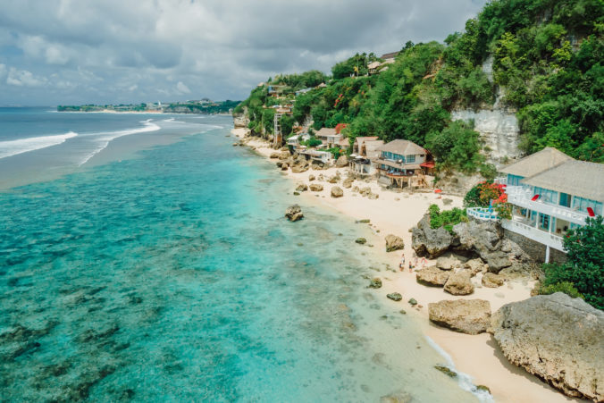 Aerial view of quiet blue ocean and beach coastline with cozy hotels on Impossibles beach in Bali