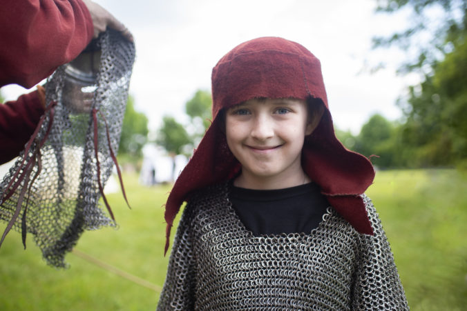 Happy boy in the ring of the middle ages on a holiday, a smiling child actor in the costume of a knight of the middle ages
