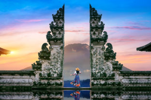 Young woman standing in temple gates at Lempuyang Luhur temple in Bali, Indonesia.