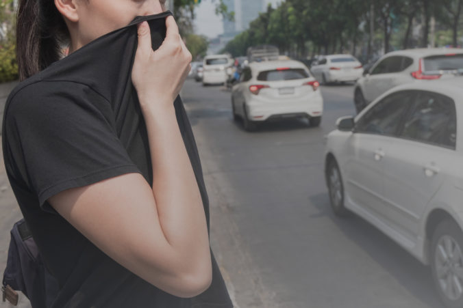 Woman closes her nose with hand because of bad traffic pollution