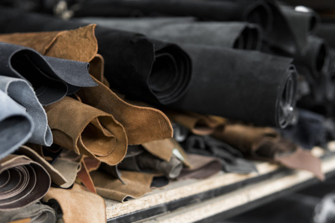 Different pieces of leather in a rolls. The pieces of the colored leathers. Rolls of natural brown and black and other leather. Raw materials for manufacture of bags, shoes, clothing and accessories.