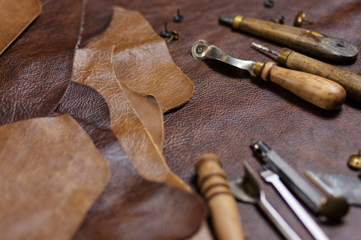 Leather craftman&#039;s work desk. Pieces of leather and working tools on a working table.
