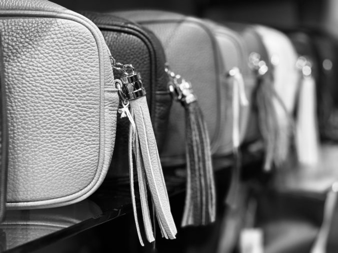 A row of women’s handbags on a retail shelf