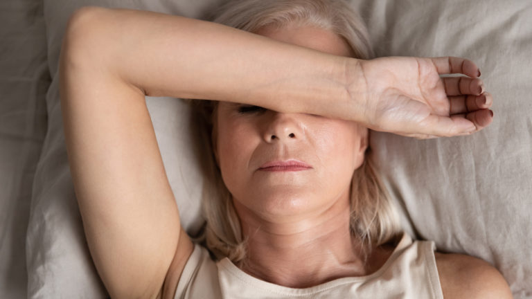 Closeup melancholic woman lying put hand on face feels unwell