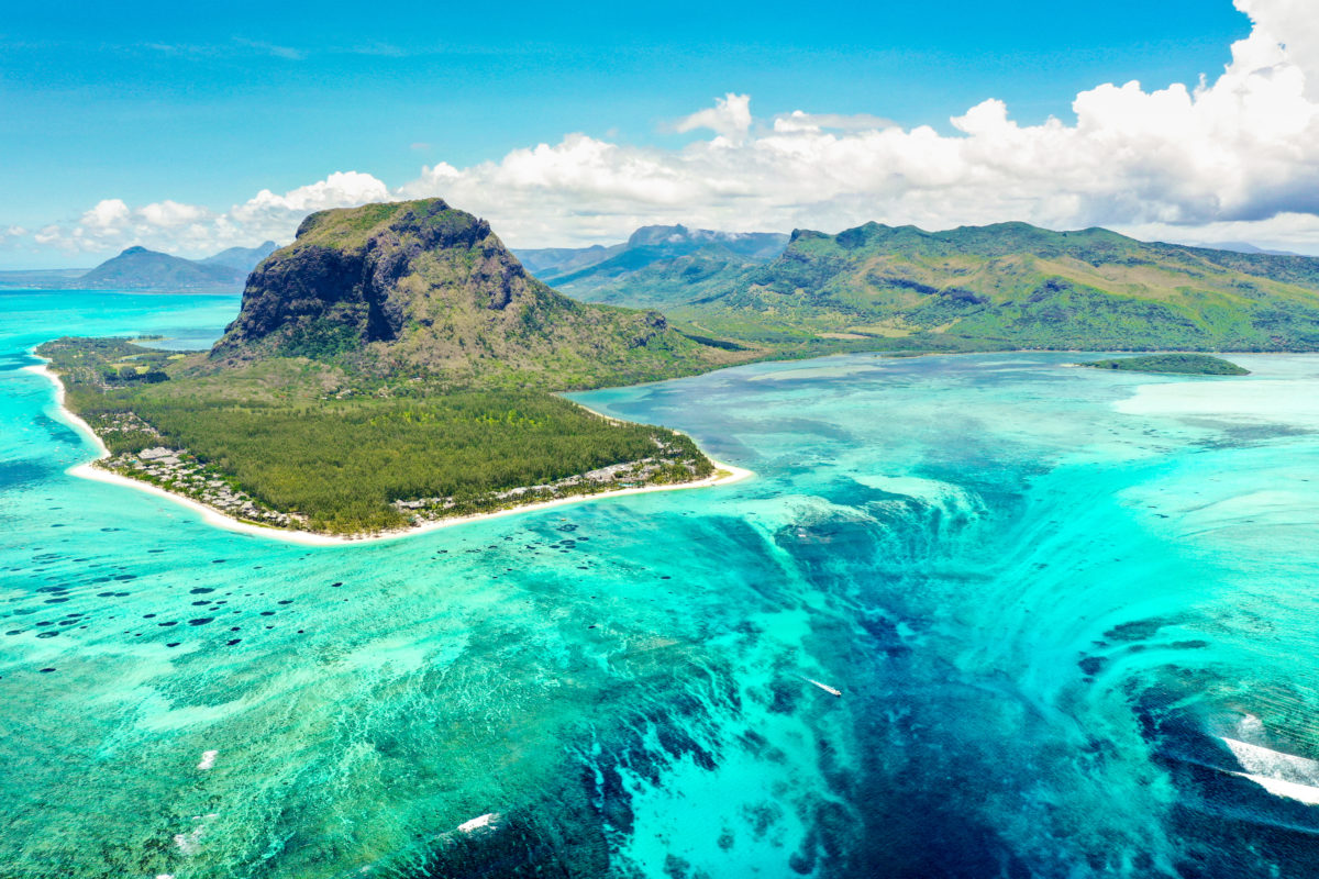 Aerial panoramic view of Mauritius island - Detail of Le Morne Brabant mountain with underwater waterfall perspective optic illusion - Wanderlust and travel concept with nature wonders on vivid filter