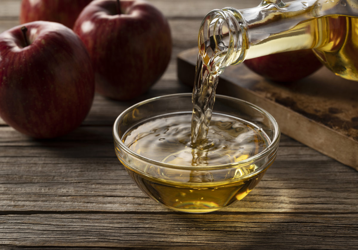 Apple vinegar in a glass container against a wooden background