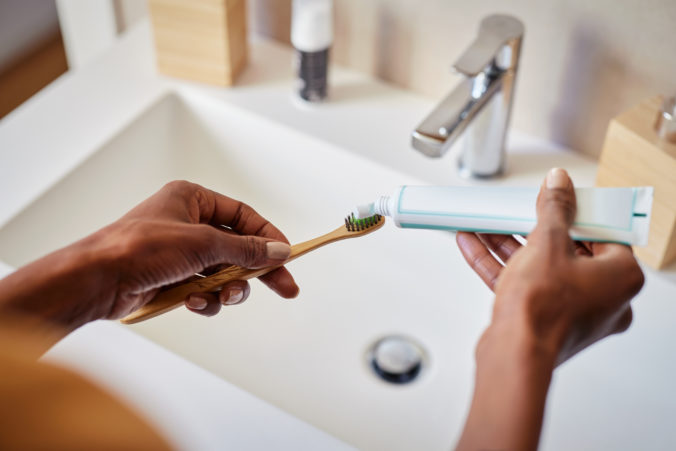 African woman put tooth paste on ecological toothbrush
