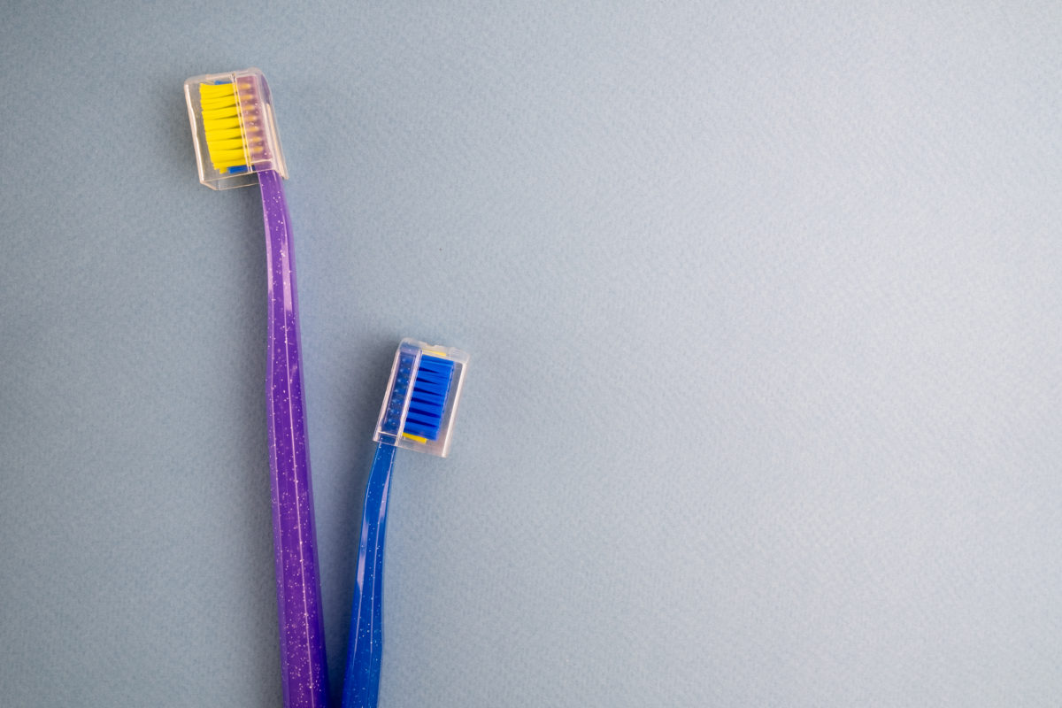 Colored toothbrushes on a gray background. Replace your old toothbrush with a new one. Old and new toothbrushes. Dental health and hygiene concept