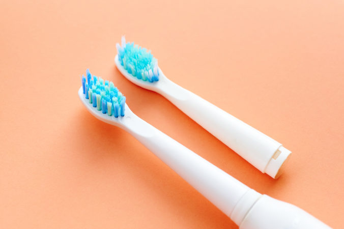Two toothbrushes on an orange background