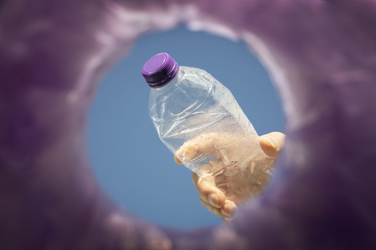 Throwing away a plastic bottle into a bin for recycling low angle view