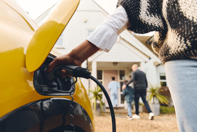 Woman plugging electric charger into car