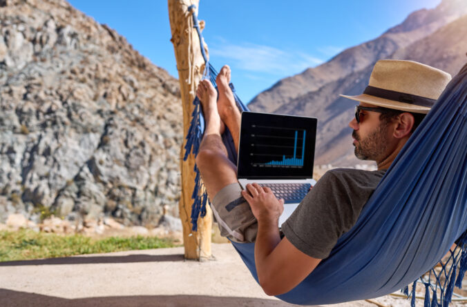 Digital nomad mature man in a lying in a hammock with a laptop