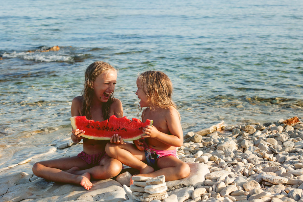 Two girls eating watermelon on the beach