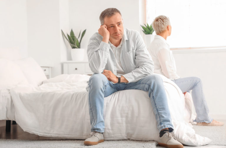 Offended mature man with his wife after quarrel in bedroom
