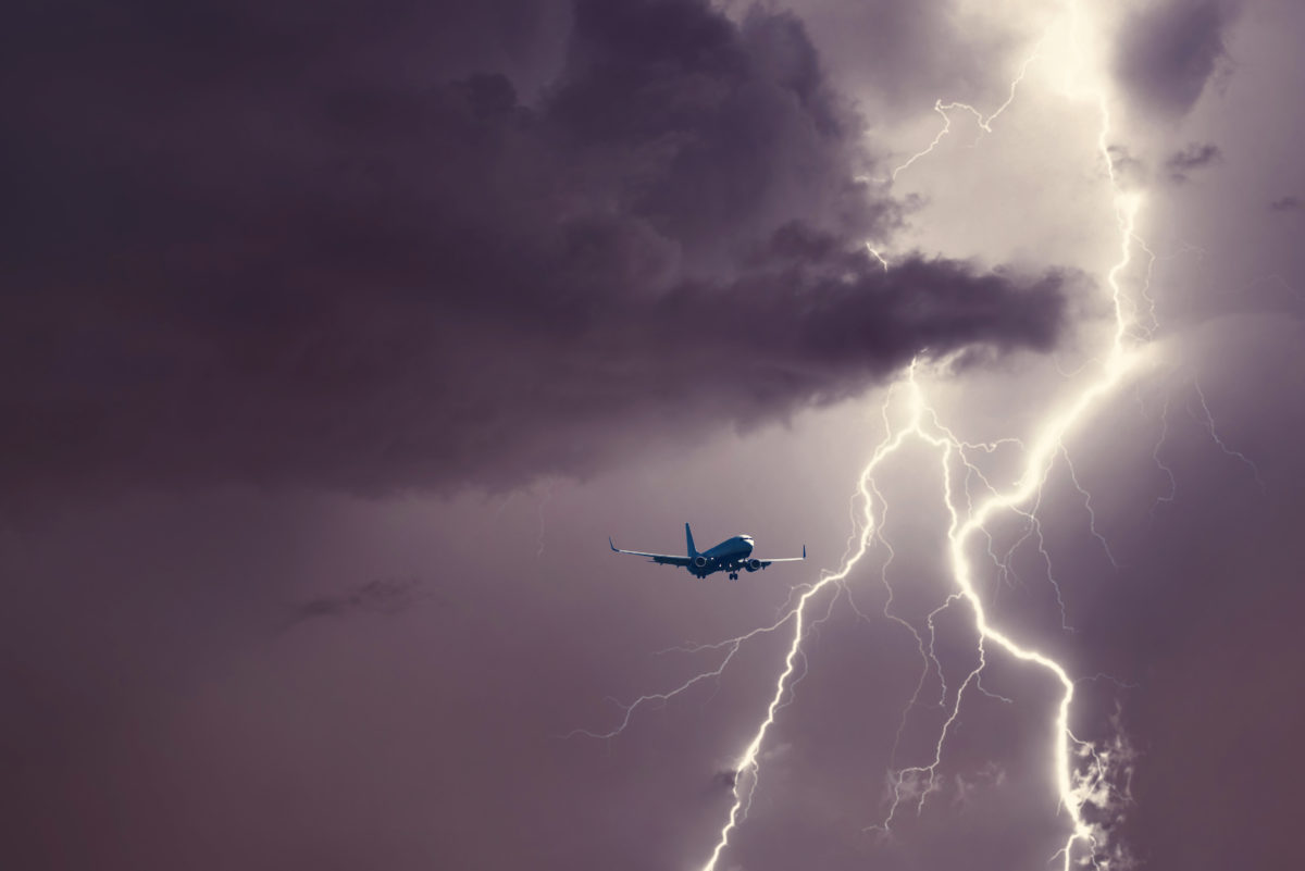 Passenger airplane landing in the stormy weather on the backdrop lightning