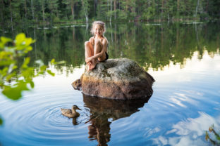 Cute little girl sitting on a rock in lake