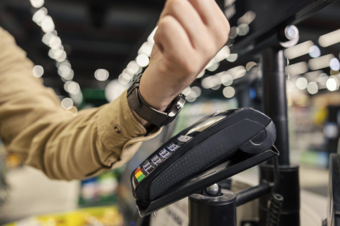 Close up of a man paying with smart watch at supermarket at self service checkout.