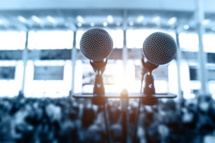 Closeup microphone in auditorium with blurred people in the background