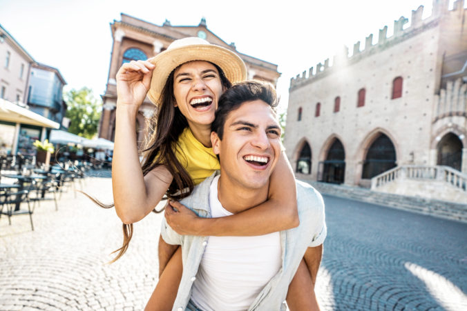 Couple of tourists having fun walking on city street at holiday - Happy friends laughing together on vacation - People and holidays concept