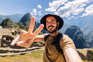 Happy young man taking selfie portrait at Macchu Picchu in Peru, South America