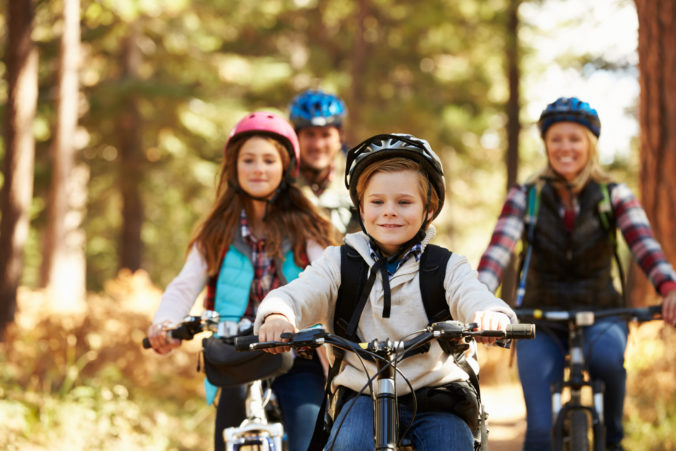 Family mountain biking on forest trail, front view, close up