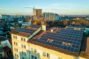 Aerial view of many photo voltaic solar panels mounted of industrial building roof.