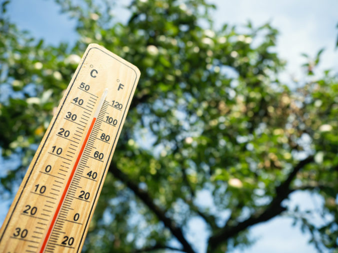 Wooden thermometer showing high temperature on sunny day.