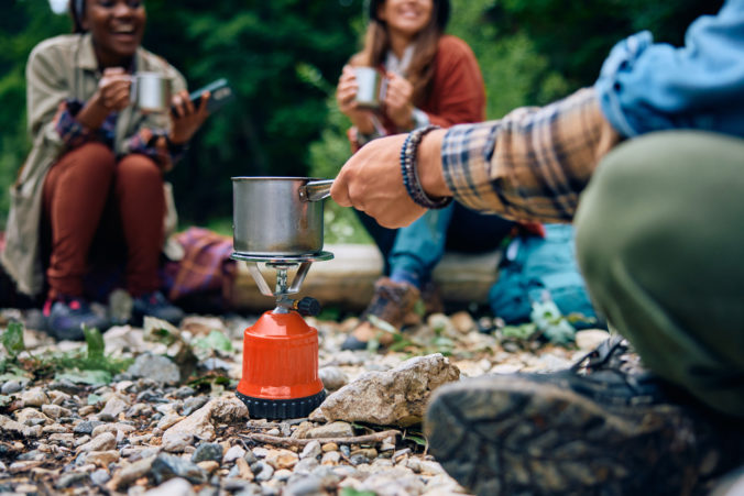 Close up of man using portable camping stove in nature.