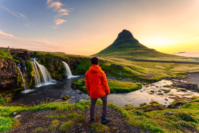 Traveler man standing with sunrise over Kirkjufell mountain in summer at Iceland