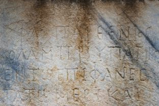 Ancient Greek inscription on a weathered stone surface with partially eroded and faded characters.