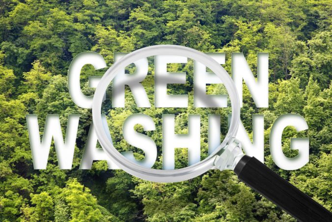 Lupa nad slovami "Green Washing" na pozadí hustých zelených stromov, symbolizujúca koncept greenwashingu, kde spoločnosti falošne tvrdia ekologické prínosy.