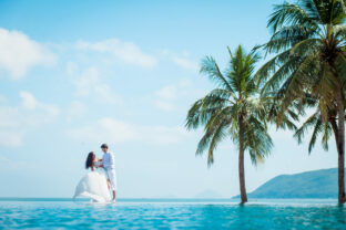 Newly married couple after wedding in luxury resort. Romantic bride and groom relaxing near swimming pool. Honeymoon.