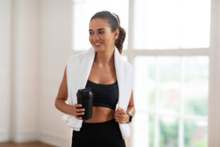 Portrait of sporty beautiful smiling woman holding shaker